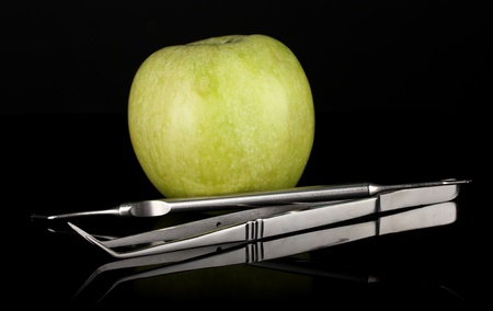 Green apple and dental tools isolated on blackの写真素材