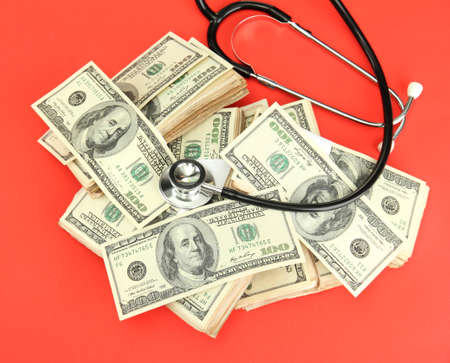 Healthcare cost concept: stethoscope and dollars on red background