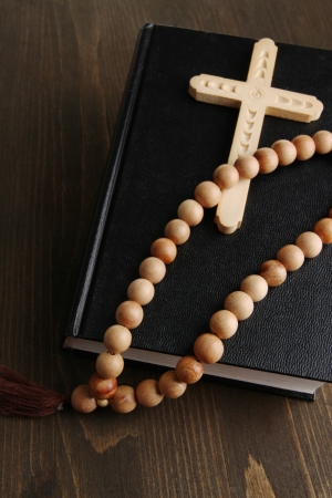 Bible, rosary and cross on wooden table close-upの写真素材