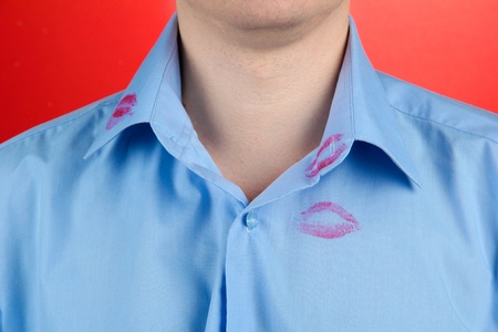 Lipstick kiss on shirt collar of man, on red backgroundの写真素材