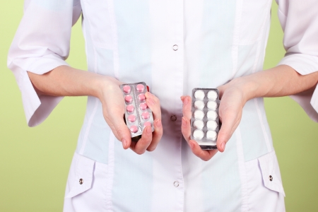 Close-up of female doctor hand holding pills, on color backgroundの写真素材