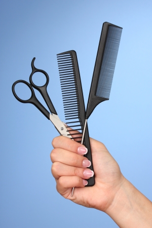 Color combs and scissors in female hand on color backgroundの写真素材