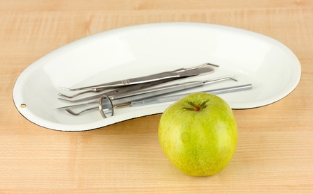 Green apple and dental tools on wooden backgroundの写真素材