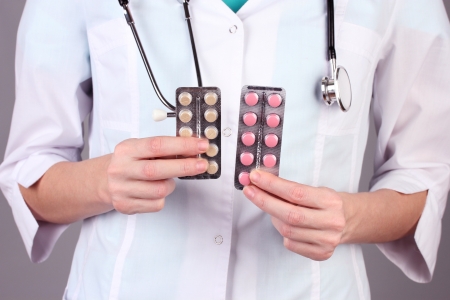 Close-up of female doctor hand holding pills, on color backgroundの写真素材