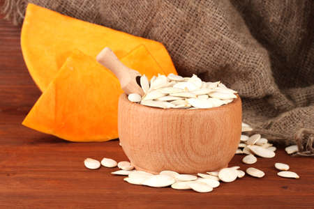 Pumpkin seeds in wooden bowl, on sackcloth backgroundの写真素材