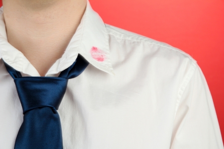 Lipstick kiss on shirt collar of man, on red backgroundの写真素材
