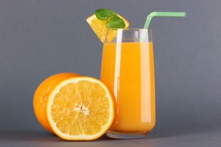 Glass of orange juice with mint and orange on grey backgroundの写真素材