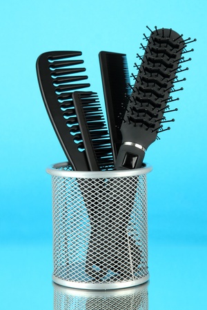 Iron basket with combs and hair brush, on color backgroundの写真素材
