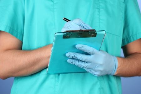 Hand of doctor with pen writing on prescription blank, on blue backgroundの写真素材