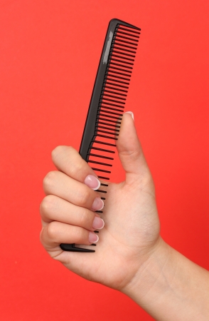 Black comb in female hand on color backgroundの写真素材
