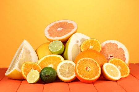 Lots ripe citrus on wooden table on orange backgroundの写真素材