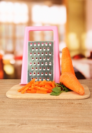 carrots with grater on cutting board on table in kitchenの写真素材