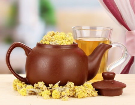 Dried herbs in teapot on wooden table, on bright background. Conceptual photo of herbal tea.の写真素材