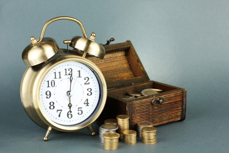 Alarm clock with coins in chest on grey backgroundの写真素材