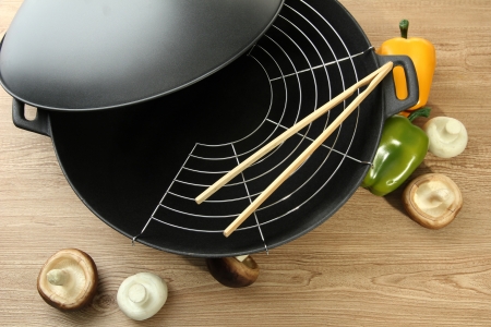 Black wok pan and vegetables on kitchen table, close upの写真素材
