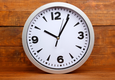 Round office clock on wooden backgroundの写真素材