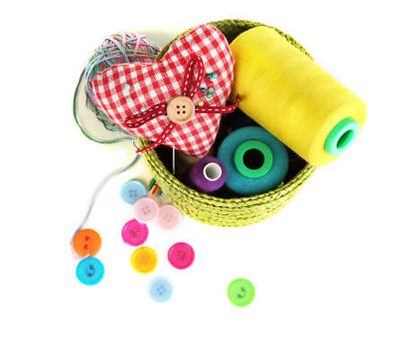 Green wicker basket with accessories for needlework isolated on white