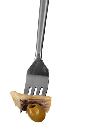 Piece of herring and olive on fork isolated on whiteの写真素材