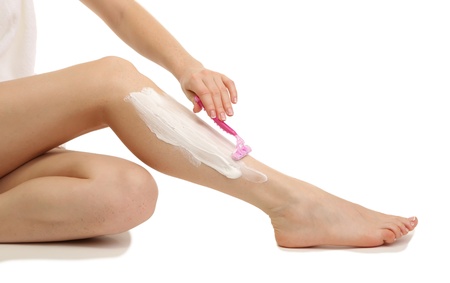 Beautiful woman is shaving her leg, isolated on whiteの写真素材