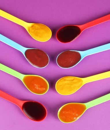 Baby puree in spoons on purple backgroundの写真素材