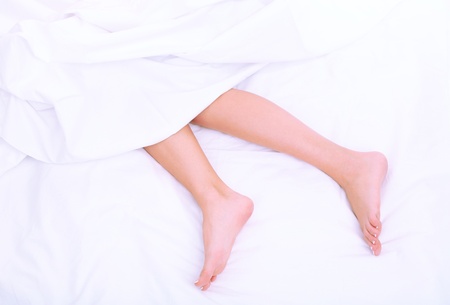 Beautiful feet of a young woman lying in bed close up