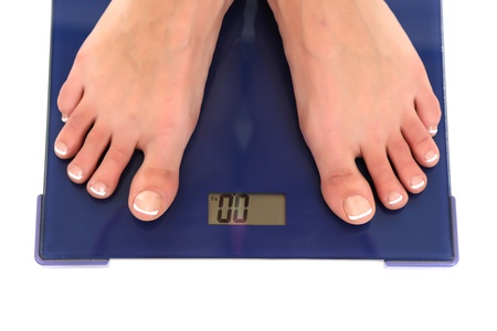 female feet standing on scale isolated on whiteの写真素材