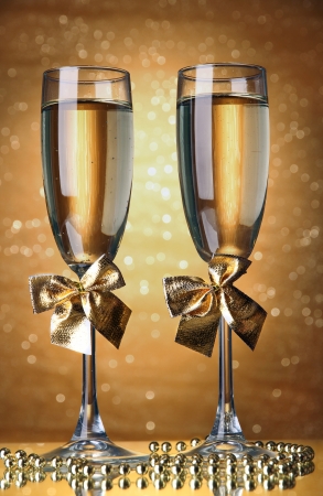 Two glasses of champagne on bright background with lightsの写真素材