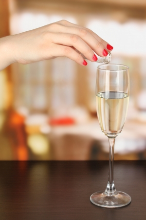 Pour something into glass with drink on wooden table on room backgroundの写真素材