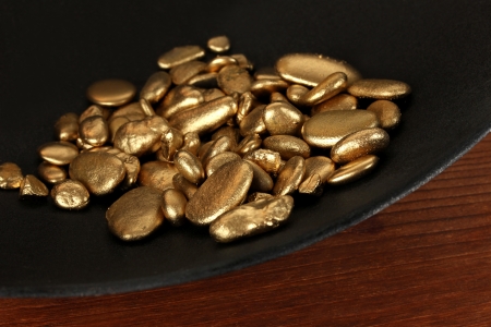Gold pan with golden nuggets inside on wooden backgroundの写真素材