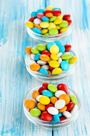 Colorful candies in glass bowls on blue wooden backgroundの写真素材