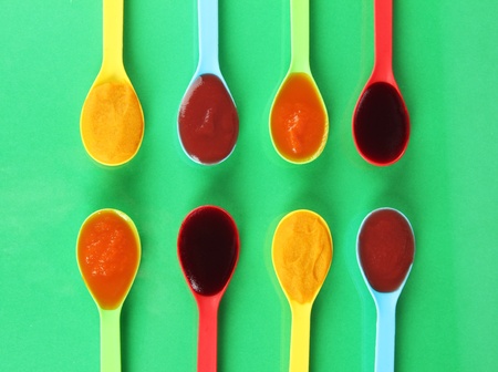 Baby puree in spoons on green backgroundの写真素材