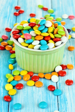 Colorful candies in bowl on blue wooden backgroundの写真素材