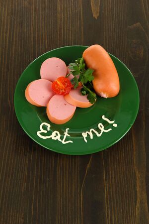 Sausage, greens, tomato on plate on wooden tableの写真素材
