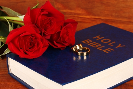 Wedding rings on bible with roses on wooden backgroundの写真素材