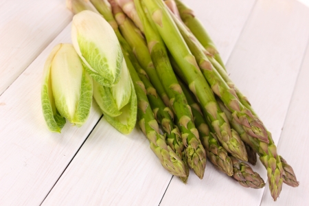 Fresh asparagus and chicory on white wooden table backgroundの写真素材