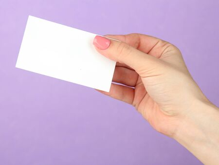 Female hand holding business card, on color backgroundの写真素材