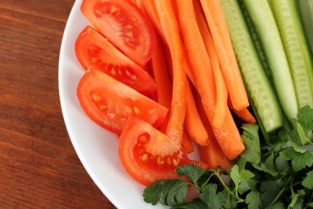 Assorted raw vegetables sticks in plate on wooden table close upの写真素材