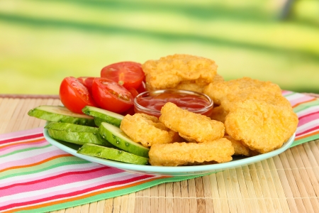 Fried chicken nuggets with vegetables and sauce on table in parkの写真素材