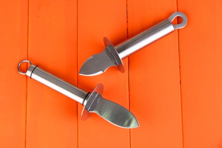 Knives for parmesan cheese and oysters, on  color wooden background