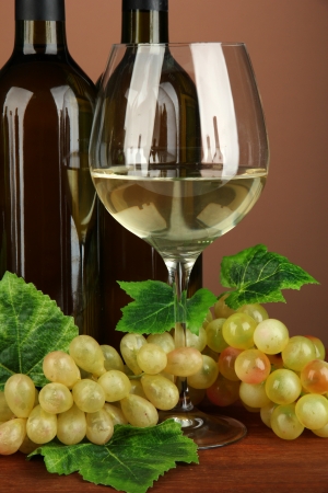 Composition of wine bottles, glass of white wine, grape on color backgroundの写真素材