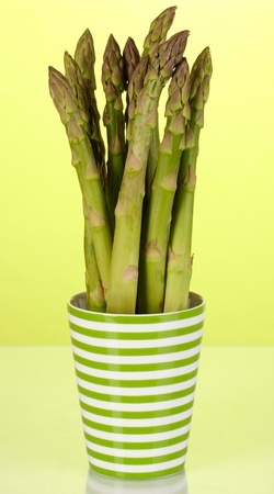 Fresh asparagus in colorful pot on green backgroundの写真素材