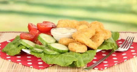 Fried chicken nuggets with vegetables and sauce on table in parkの写真素材