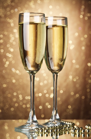 Two glasses of champagne on bright background with lightsの写真素材