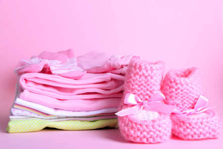 Pile of baby clothes on pink backgroundの写真素材