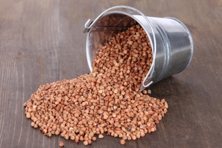 Overturned bucket with grains on wooden backgroundの写真素材