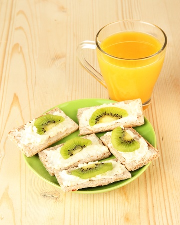 Tasty canapes with cheese and kiwi, on color plate, on wooden backgroundの写真素材