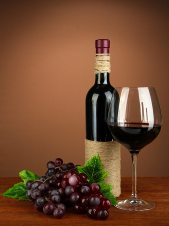 Composition of wine bottle, glass of red wine, grape on color backgroundの写真素材