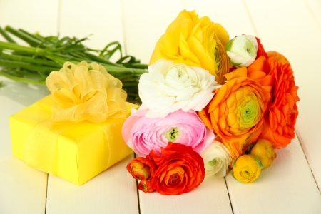 Ranunculus (persian buttercups) and gift, on white wooden backgroundの写真素材