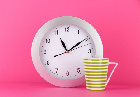Cup tea and clock on pink backgroundの写真素材