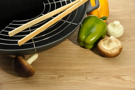 Black wok pan and vegetables on kitchen table, close upの写真素材